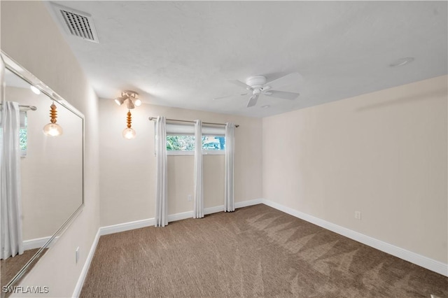 carpeted empty room featuring visible vents, baseboards, and ceiling fan