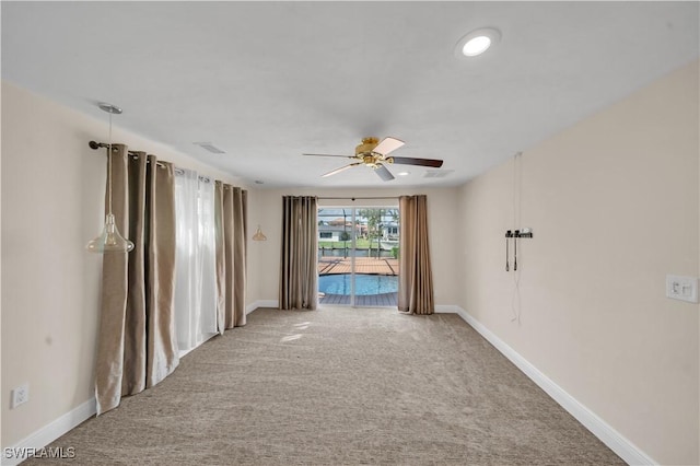 carpeted spare room featuring baseboards and ceiling fan