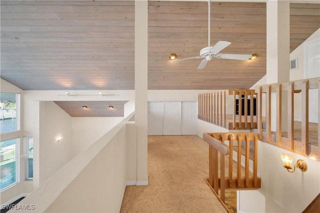 corridor with an upstairs landing, visible vents, wood ceiling, and vaulted ceiling