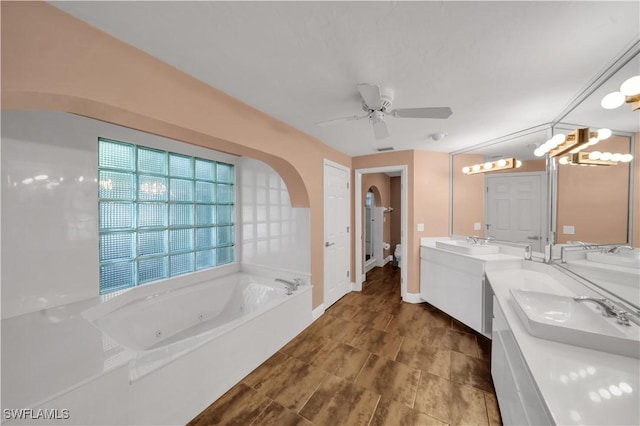 full bath with a sink, double vanity, a whirlpool tub, and ceiling fan with notable chandelier