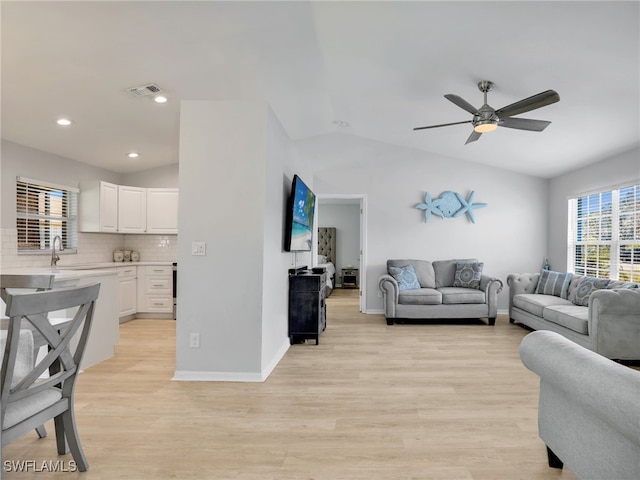 living room featuring visible vents, light wood-style flooring, a ceiling fan, baseboards, and lofted ceiling