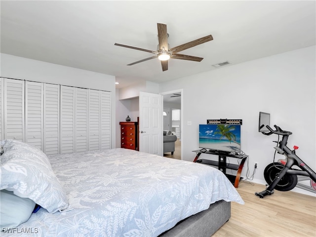 bedroom with a ceiling fan, wood finished floors, visible vents, and a closet