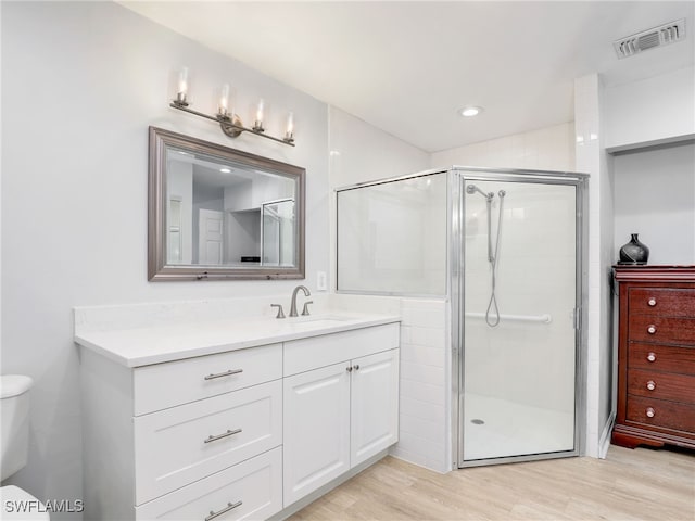 bathroom featuring vanity, wood finished floors, visible vents, a shower stall, and toilet