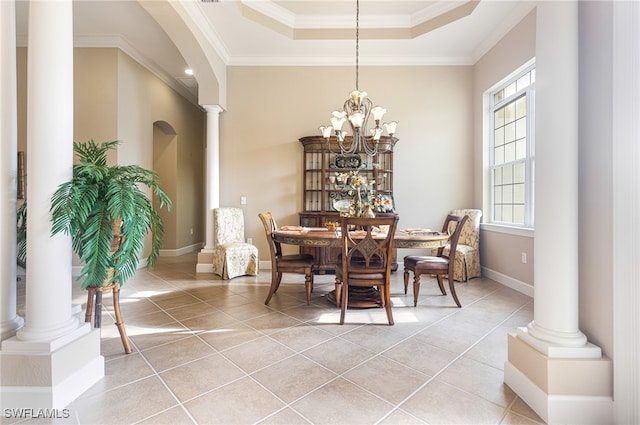 dining room with light tile patterned floors, a raised ceiling, ornate columns, and ornamental molding