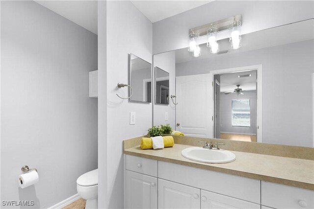 821 Casino Ave, Lehigh Acres, FL 33971 - bathroom with toilet, vanity, baseboards, a chandelier, and a ceiling fan