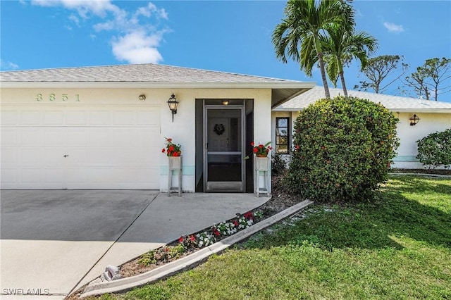 doorway to property with stucco siding, a lawn, roof with shingles, and concrete driveway