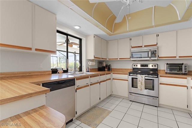 kitchen featuring light tile patterned floors, a toaster, a sink, stainless steel appliances, and light countertops