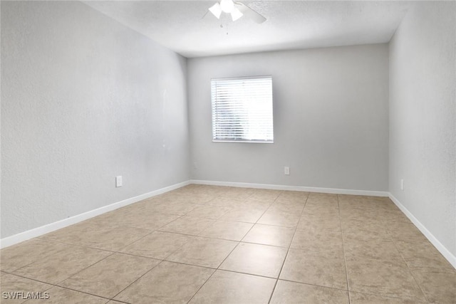 spare room featuring light tile patterned floors, a ceiling fan, and baseboards