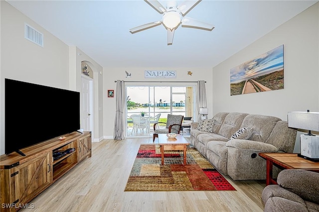 living room featuring light wood-style flooring, a ceiling fan, visible vents, and baseboards