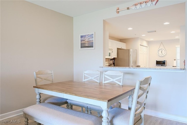 dining space with recessed lighting, light wood-style flooring, and baseboards