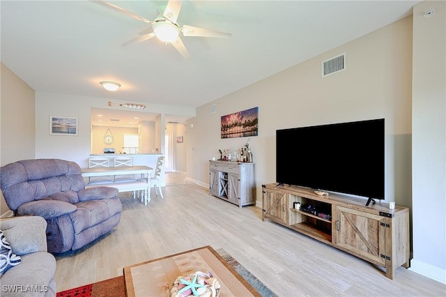 living area with visible vents, ceiling fan, baseboards, and light wood-style floors