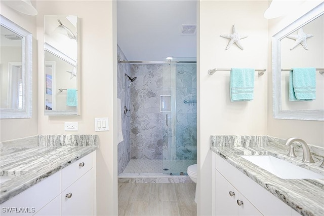 bathroom with vanity, toilet, visible vents, and a stall shower