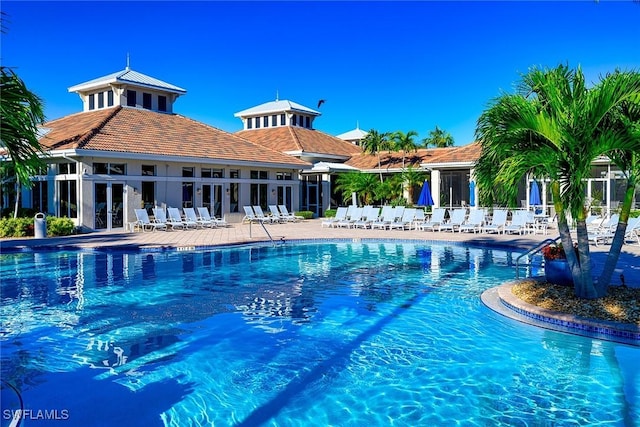 community pool with a patio area, fence, and french doors