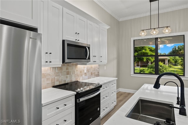 kitchen with a sink, backsplash, stainless steel appliances, crown molding, and light stone countertops