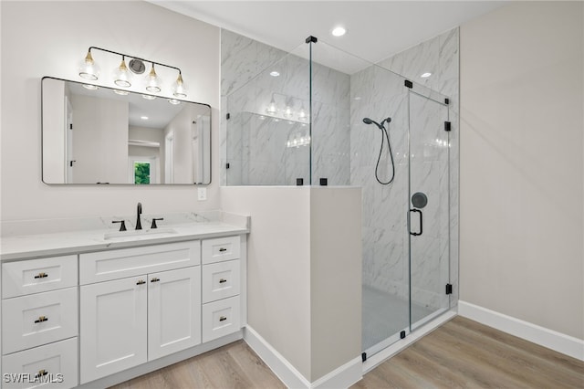 bathroom with vanity, wood finished floors, baseboards, a marble finish shower, and recessed lighting