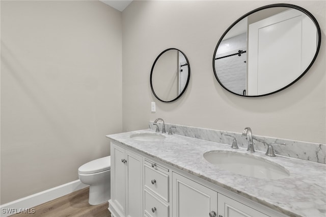 bathroom with wood finished floors, toilet, baseboards, and a sink