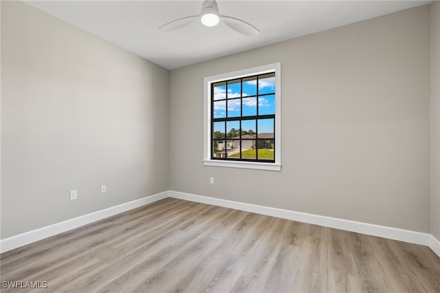 spare room featuring baseboards, light wood finished floors, and ceiling fan