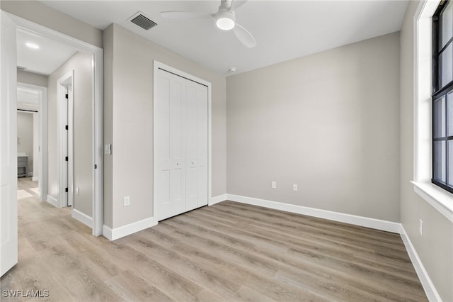 unfurnished bedroom featuring light wood-type flooring, visible vents, a ceiling fan, a closet, and baseboards