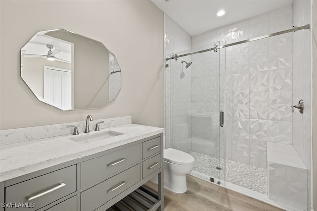 full bathroom featuring vanity, toilet, wood finished floors, and a stall shower