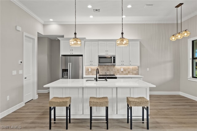 kitchen with a sink, stainless steel appliances, visible vents, and ornamental molding