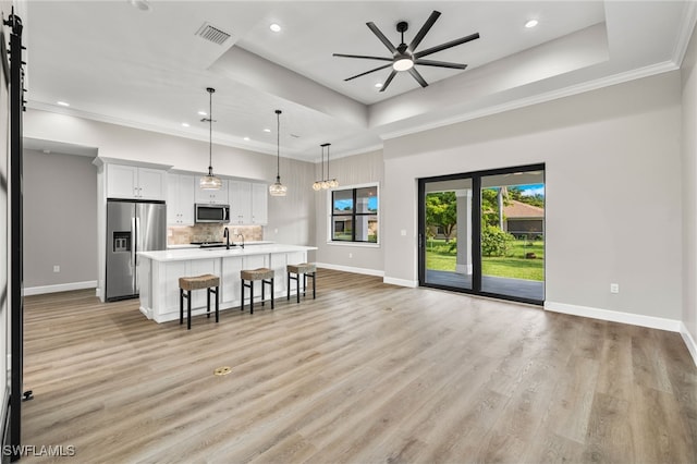 kitchen with a tray ceiling, open floor plan, visible vents, and stainless steel appliances