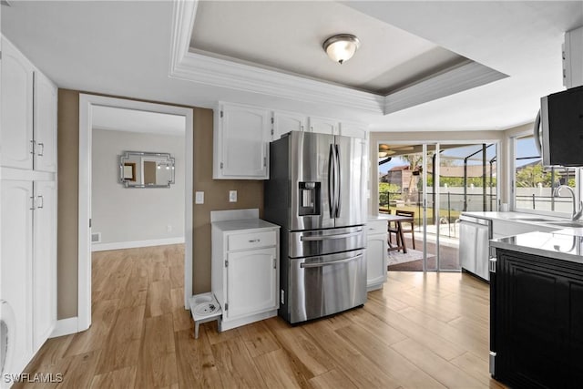 kitchen with white cabinetry, stainless steel appliances, light wood finished floors, a raised ceiling, and light countertops