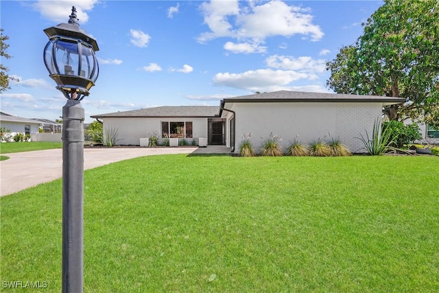 view of front of property featuring stucco siding, driveway, and a front lawn