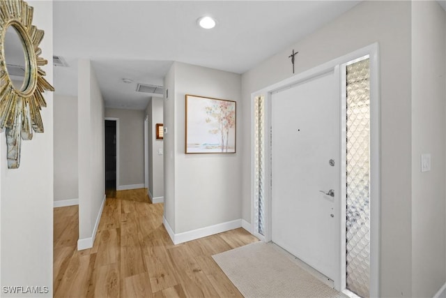 foyer entrance with light wood-style flooring, visible vents, and baseboards