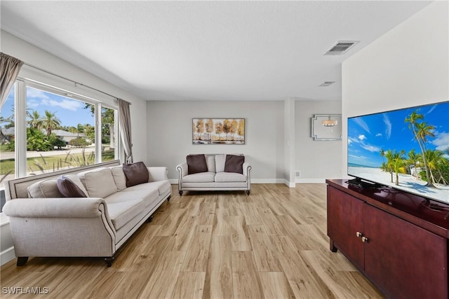 living room featuring light wood-style floors, visible vents, and baseboards