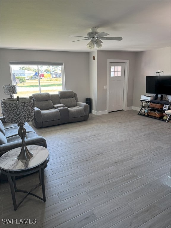 living room with baseboards, a ceiling fan, and wood finished floors