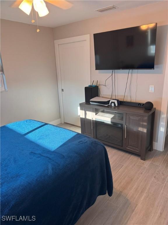 bedroom with baseboards, visible vents, light wood finished floors, and ceiling fan