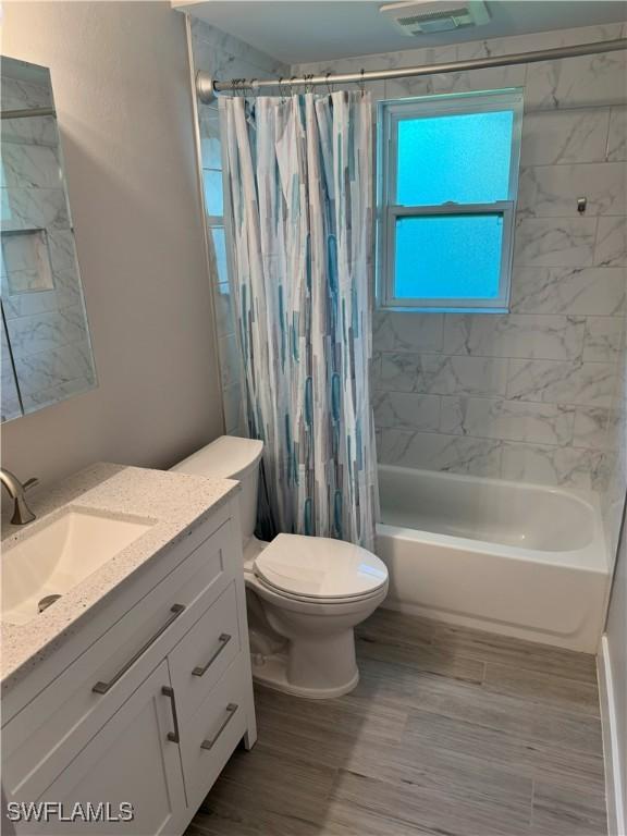 bathroom with visible vents, vanity, toilet, and shower / tub combo with curtain