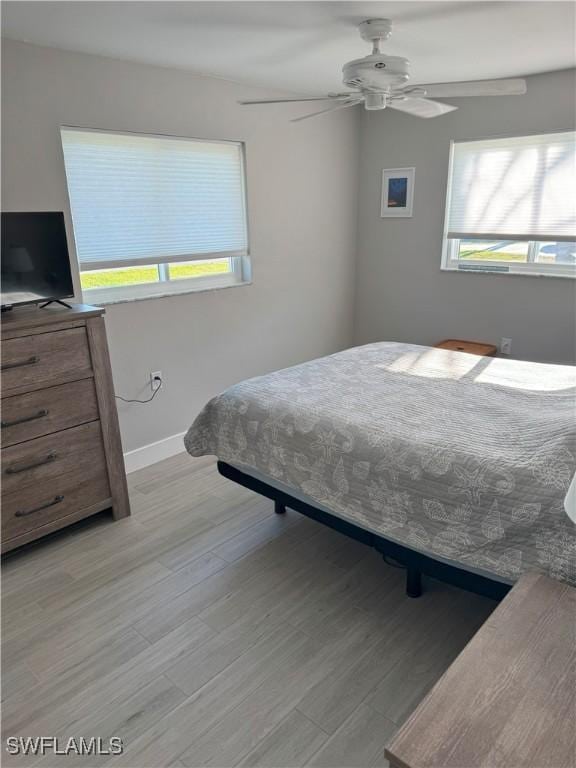 bedroom featuring baseboards, light wood-style flooring, and a ceiling fan