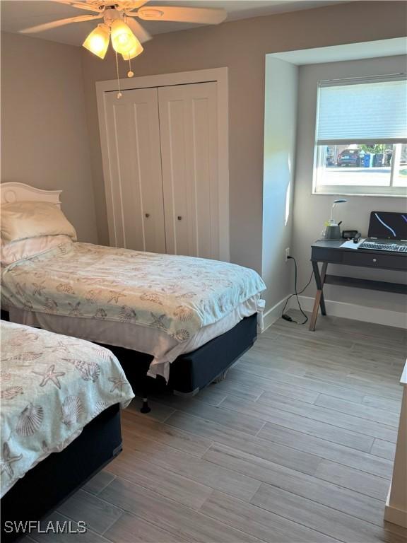 bedroom with wood finish floors, a closet, baseboards, and ceiling fan