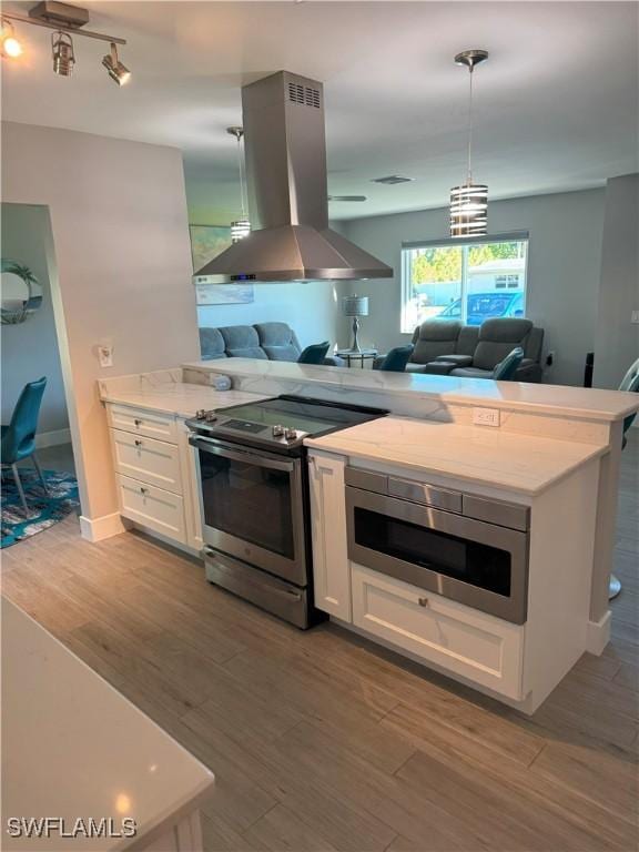 kitchen featuring stainless steel appliances, open floor plan, island range hood, and white cabinetry