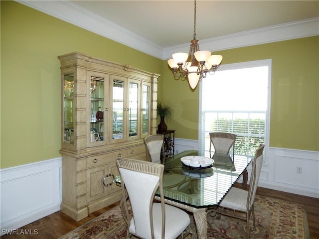 dining space featuring wood finished floors, a wainscoted wall, and a chandelier