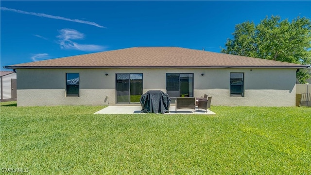 rear view of house featuring stucco siding, a patio area, and a lawn
