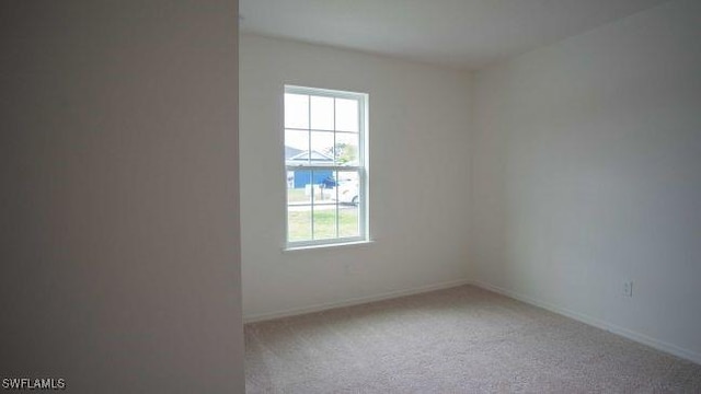 carpeted empty room featuring baseboards