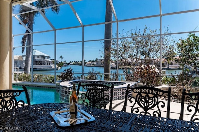 view of patio / terrace featuring glass enclosure, a water view, and a pool with connected hot tub