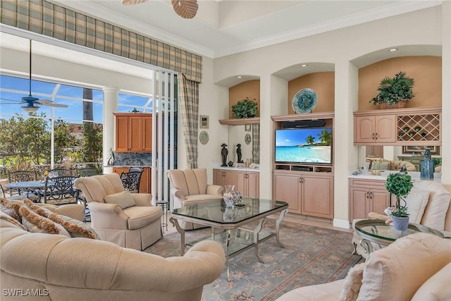 living area featuring light tile patterned flooring, ornamental molding, and a ceiling fan