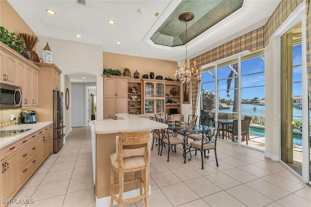 kitchen featuring light tile patterned floors, arched walkways, stainless steel appliances, light countertops, and a water view