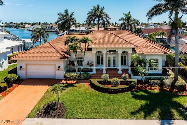 mediterranean / spanish-style home with stucco siding, a front lawn, french doors, concrete driveway, and an attached garage
