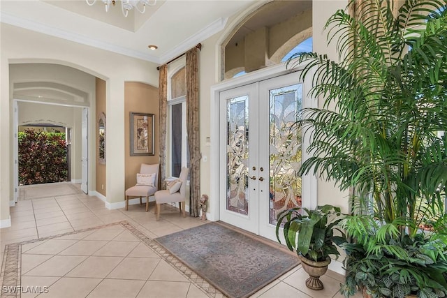 entryway featuring baseboards, ornamental molding, french doors, light tile patterned flooring, and plenty of natural light