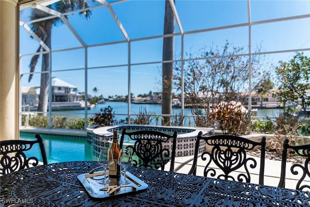 view of patio with glass enclosure, a pool with connected hot tub, and a water view