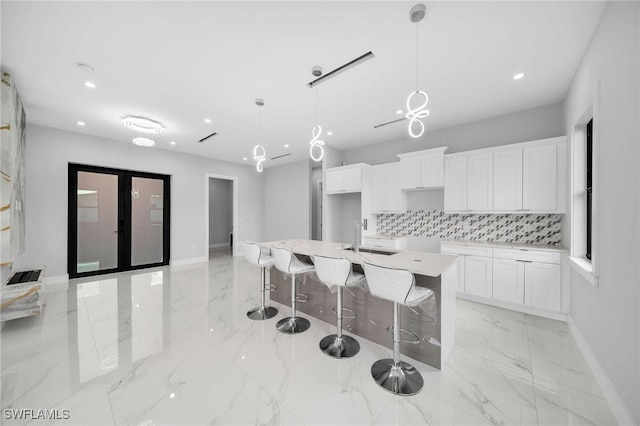 kitchen with white cabinetry, tasteful backsplash, marble finish floor, and a center island