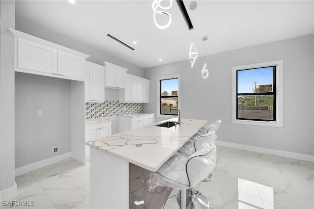 kitchen with white cabinets, baseboards, backsplash, and a sink