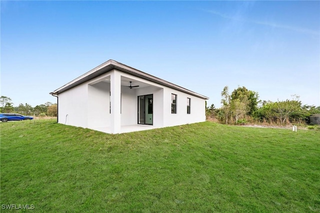 rear view of house featuring stucco siding, a patio, a ceiling fan, and a yard