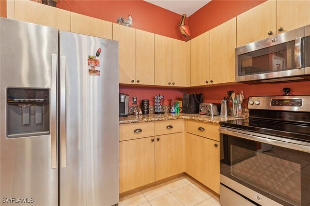 20854 Wheelock Dr, North Fort Myers, FL 33917 - kitchen featuring light tile patterned flooring, light stone countertops, light brown cabinetry, and stainless steel appliances