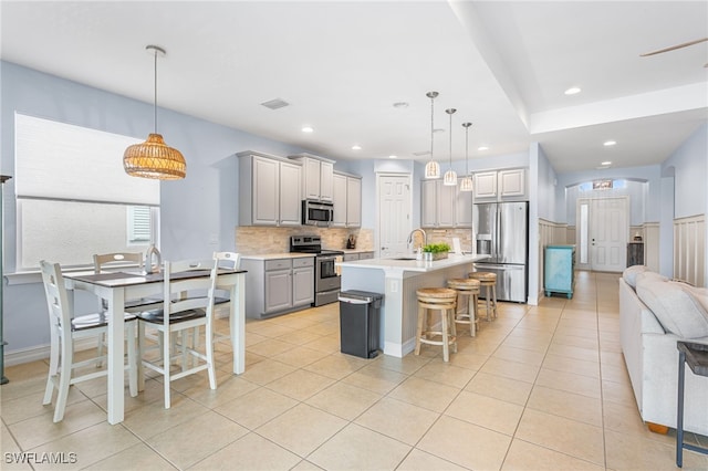 13104 Silver Thorn Loop, North Fort Myers, FL 33903 - kitchen with stainless steel appliances, open floor plan, decorative backsplash, light countertops, and a kitchen bar