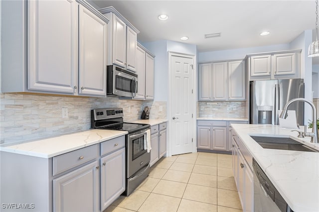13104 Silver Thorn Loop, North Fort Myers, FL 33903 - kitchen with appliances with stainless steel finishes, gray cabinets, a sink, light stone countertops, and light tile patterned floors